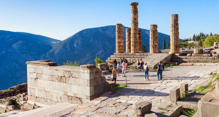 Les visiteurs explorant les colonnes de pierre et les ruines du Temple d'Apollon à Delphes.