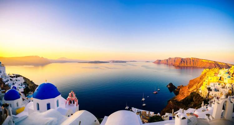 Gouden zonsopgang panorama van de Santorini caldera met iconische blauwe koepels.