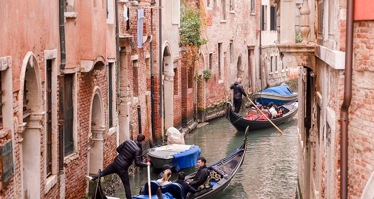 Les gondoliers naviguent dans d'étroits canaux entre les bâtiments vénitiens rustiques