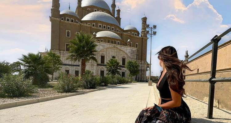 Femme assise devant une grande mosquée.