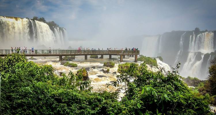 Tourists observing Iguazu Falls from a walkway.