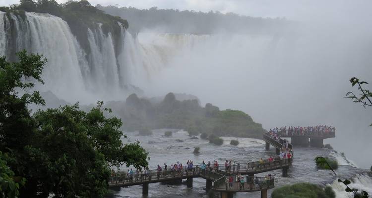 Walkway over looking vast Iguazu Falls surrounded by mist.
