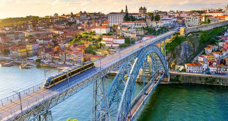 A stunning view of a bridge over a river with a cityscape in the background, under a colorful sky.