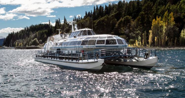 Bote en un lago con orilla boscosa.