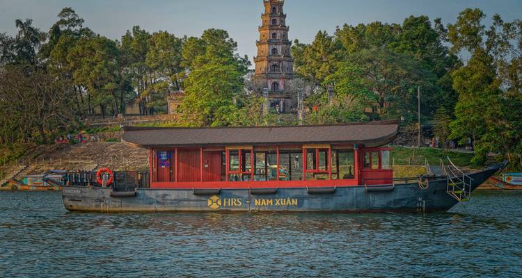 Bateau naviguant sur une rivière avec une tour historique en arrière-plan.