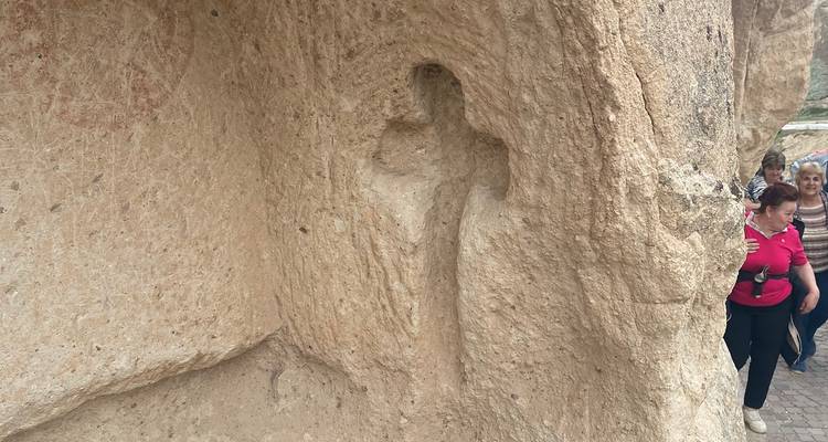 Kruis uitgesneden in een rotsoppervlak met mensen in de buurt.