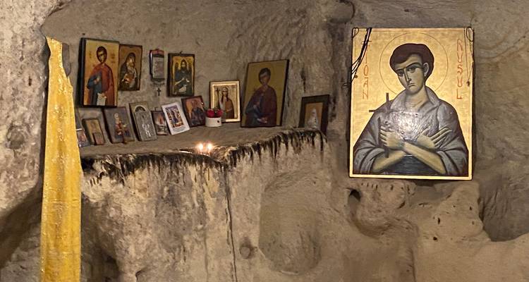 Interieur van een grotkapel met iconen en kaarsen.