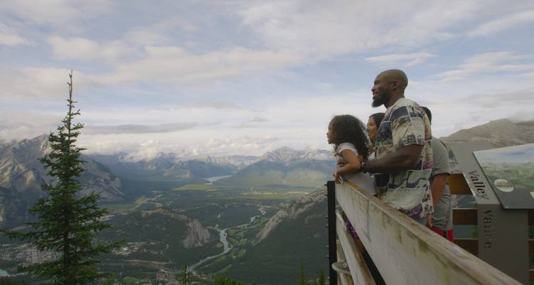 Familie geniet van een schilderachtig bergzicht vanaf een houten platform.