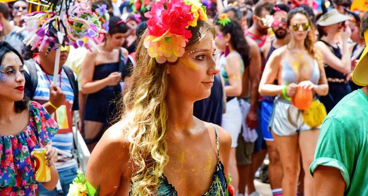 Kleurrijke gekostumeerde deelnemer met bloemen hoofdtooi viert tijdens Braziliaans carnaval straatfeest
