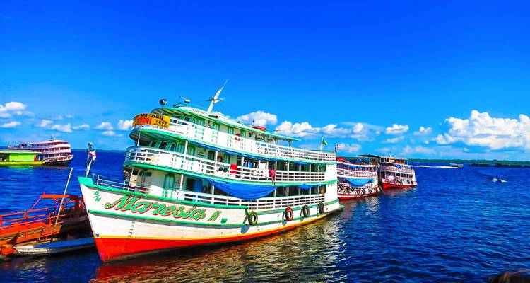 Kleurrijke rivierpersoneelsboten aangemeerd aan de Amazone onder een levendige blauwe hemel