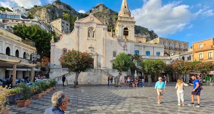 A lively town square with a historical building and people walking.