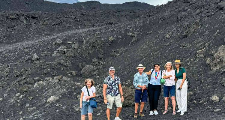 Group of people standing on a barren volcanic landscape.