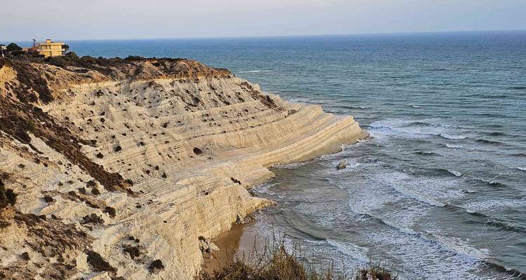 A cliffside with unique rock formations by the sea.