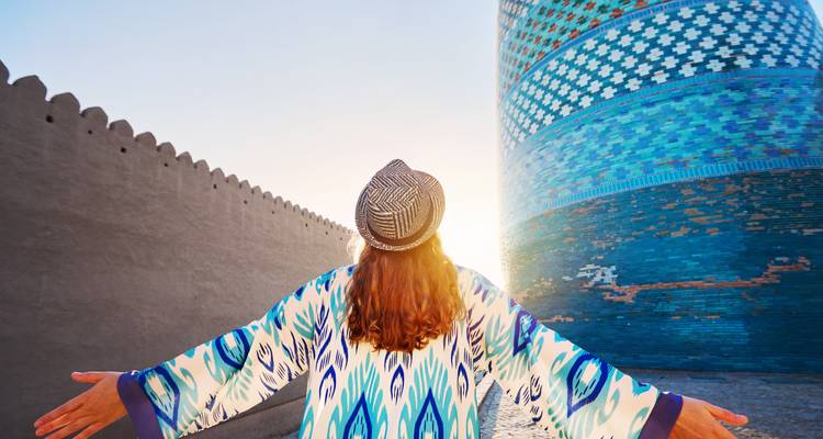 Une personne en tenue traditionnelle face à une tour bleu vibrant et turquoise.