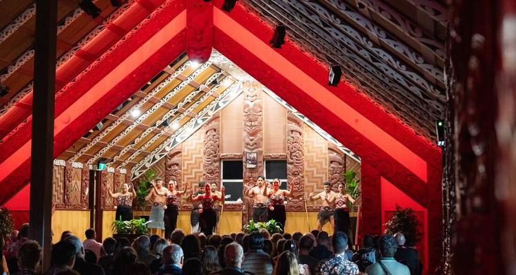 Una actuación cultural maorí dentro de un salón de madera bellamente tallado.