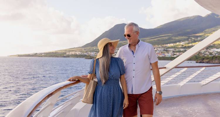 Couple se promenant sur le pont d'un navire de croisière avec des îles en vue.