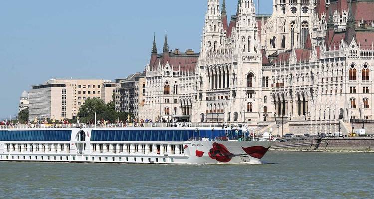 River cruise ship passing in front of the ornate Hungarian Parliament Building on the Danube in Budapest.