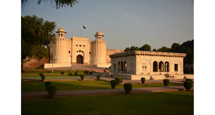 Historic Lahore Fort gate and marble baradari surrounded by manicured lawns at golden hour.