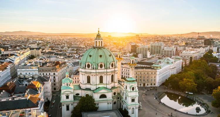 Stadtbild von Wien mit einer prominenten Kathedrale bei Sonnenuntergang.