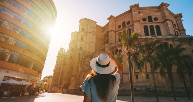 Rückansicht einer Person, die ein historisches Gebäude in Málaga betrachtet.