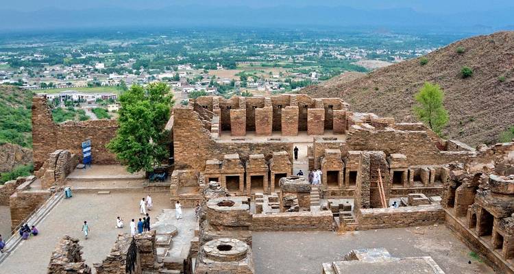 Les visiteurs se promènent parmi les ruines au sommet de la colline d'un ancien complexe monastique surplombant une vaste vallée verdoyante.