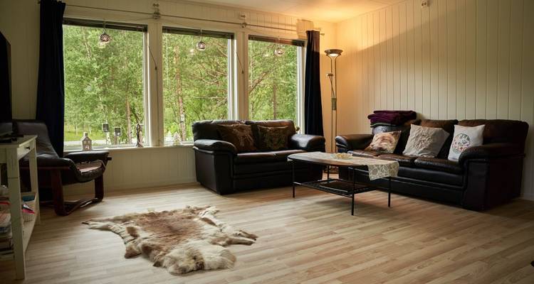Gemütliches, mit Holzmöbeln eingerichtetes Wohnzimmer mit Blick nach draußen.