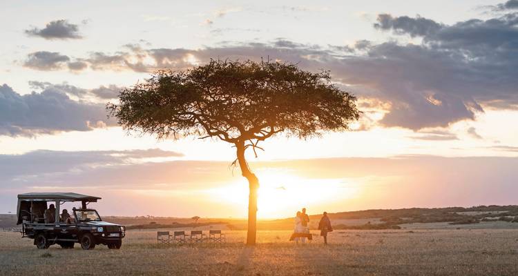 Safari-Szene mit einem Fahrzeug und Menschen in der Savanne bei Sonnenuntergang.