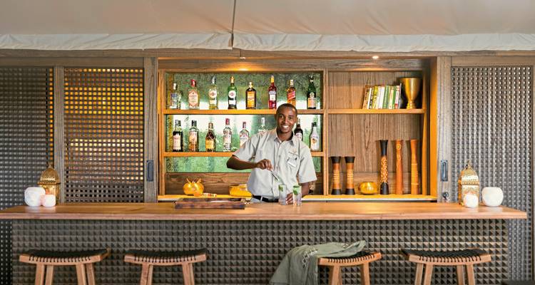 Barkeeper bereitet ein Getränk an einer gut bestückten Bar zu.