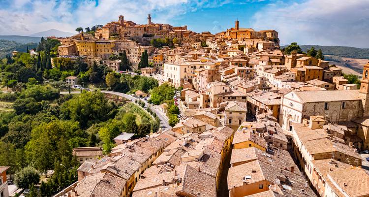 Vue aérienne d'une ville européenne médiévale avec des toits en terre cuite et des collines.