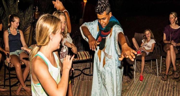 People dancing and sitting in a night setting with rugs.