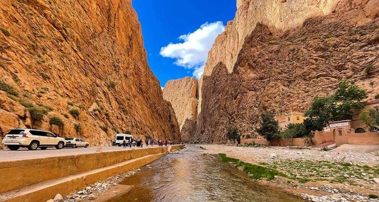 A narrow canyon with a river and vehicles.