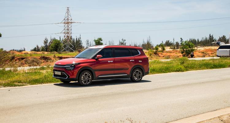 Red car driving on a road with a scenic backdrop.