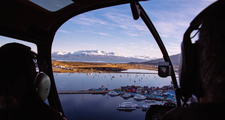 Vue depuis la cabine d'hélicoptère d'Ushuaïa avec la baie et les montagnes enneigées.