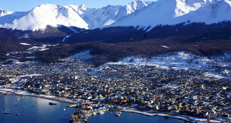 Vue panoramique de la ville d'Ushuaia avec des montagnes enneigées en arrière-plan.