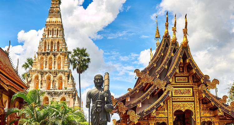 Traditionele Thaise architectuur met een torenhoge spits onder een blauwe hemel.