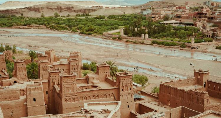 Pueblo antiguo junto a un río con vegetación.