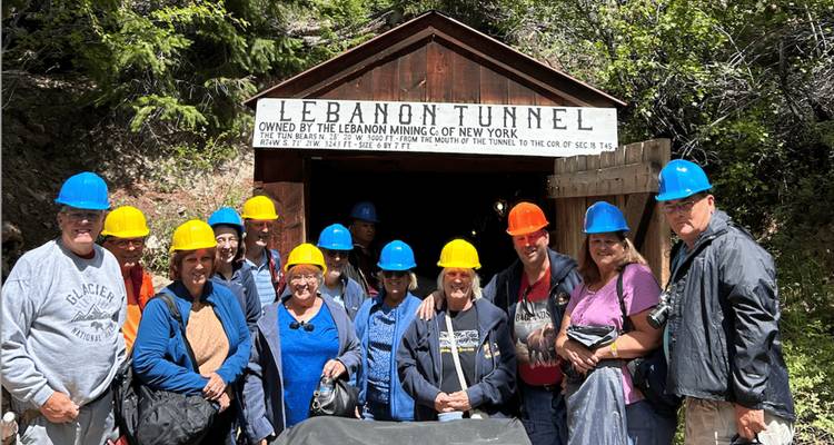 Touristengruppe mit farbigen Schutzhelmen versammelt sich am Eingang des historischen Bergwerks Lebanon Tunnel.