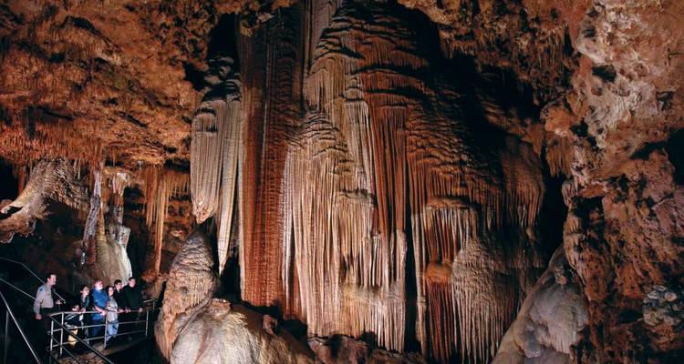 Turistas explorando una cueva grande con estalagmitas.