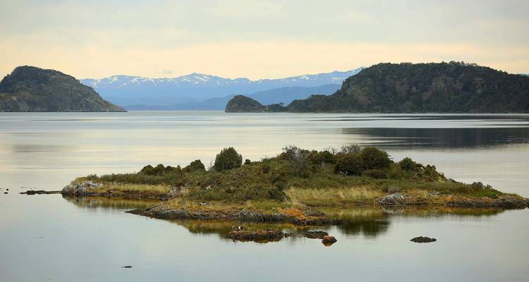 Isolated island in a tranquil lake with mountains.
