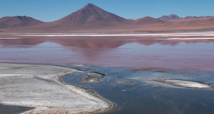 Vue panoramique d'un lagon coloré avec des reflets de montagnes.