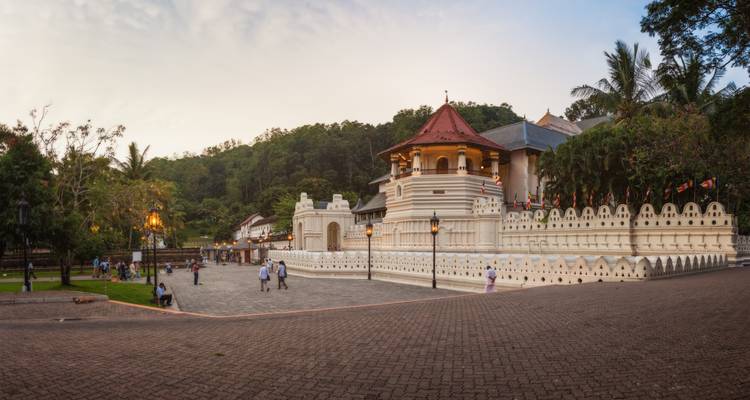 Panoramisch uitzicht op de historische Tempel van de Tand in Kandy bij zonsondergang met bezoekers die buiten wandelen.