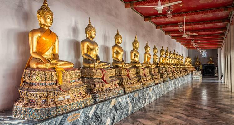 A row of golden Buddha statues in a temple corridor.
