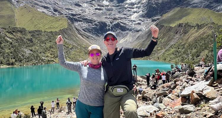 Deux randonneurs célébrant au bord d'un lac turquoise entouré de montagnes.