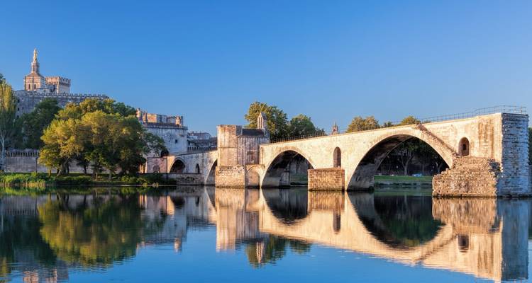 Historic arched bridge over a river reflecting the adjacent building.