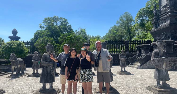 Famille posant parmi les statues de guerriers en pierre dans la cour d'un complexe de tombeaux royaux vietnamiens.