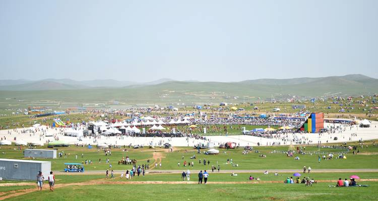Ein überfülltes Festival mit vielen Zelten und Menschen auf einem offenen Feld.