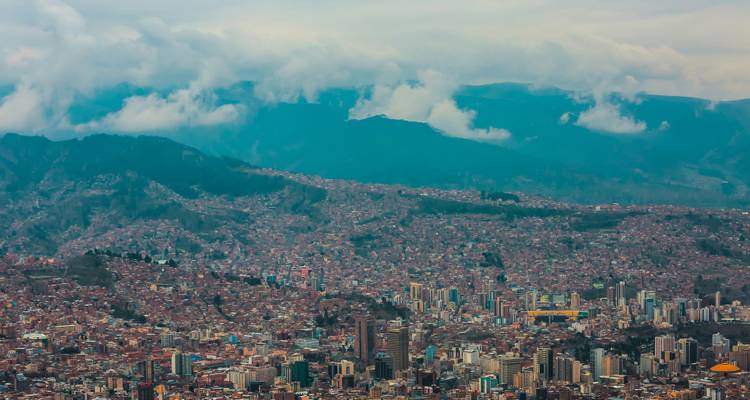 Panorama aérien de La Paz s'étendant à travers une vallée escarpée sous les pics andins brumeux et les nuages bas.