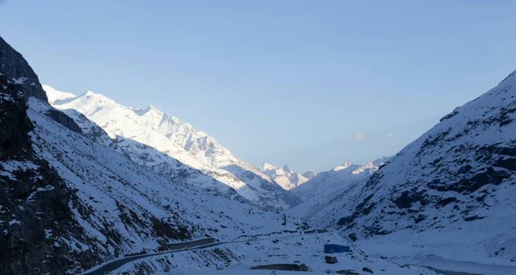 Montagnes enneigées avec une route qui serpente à travers la vallée.