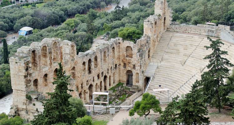 Ein antikes Freilichttheater mit Blick auf Bäume dahinter.