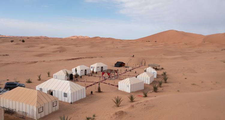 Site de glamping dans le désert avec tentes et dunes pittoresques.